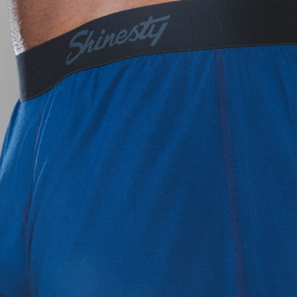 Waistband of royal blue boxer shorts, Shinesty script on the black elastic band, fabric hanging loose below