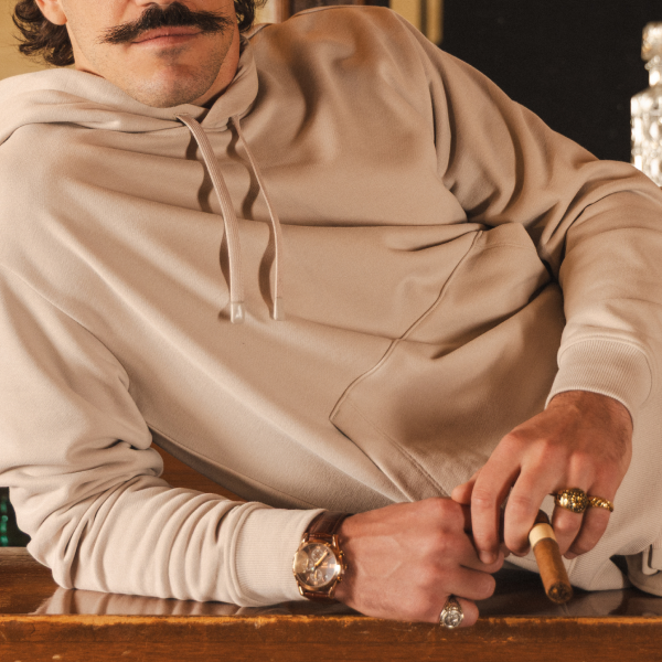 Cigar being cut by a man in an oatmeal Shinesty hoodie, ribbed cuffs and drawstrings in frame