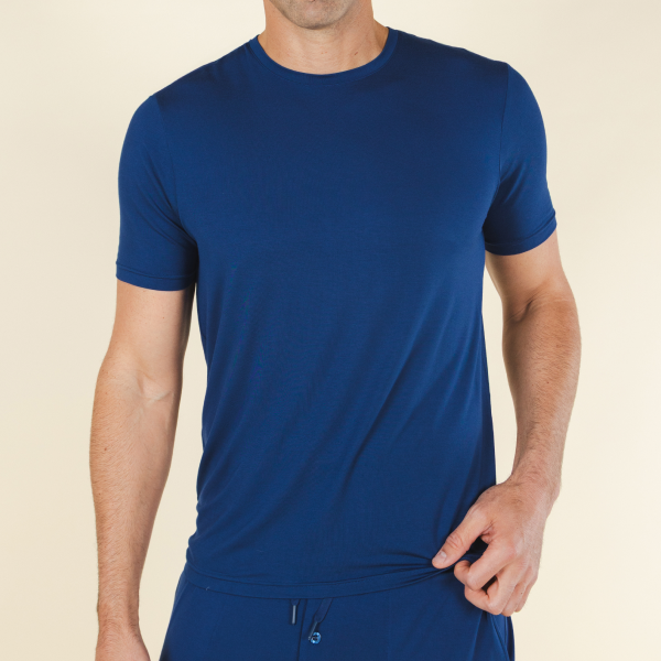 Standing against a cream wall in a royal blue short-sleeve MicroModal pajama tee