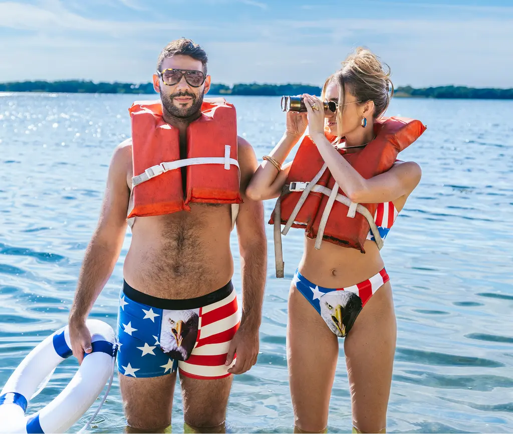 A couple in matching American flag print underwear wearing life jackets in the water