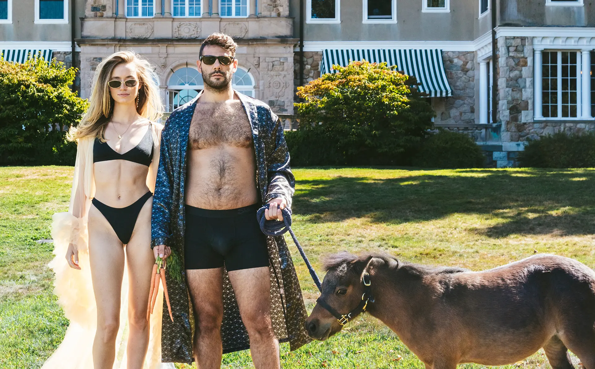 A couple in matching Shinesty underwear standing outside a mansion with a miniature horse